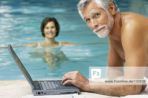 Mann und Frau im Schwimmbad mit Computer