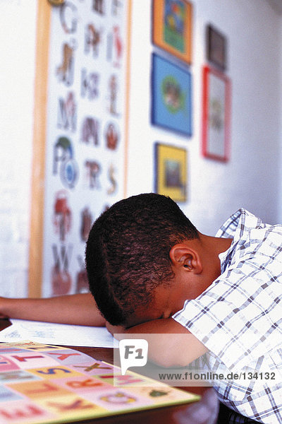 Junge schläft bei den Hausaufgaben