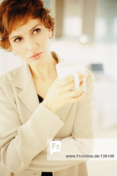 Eine nachdenkliche Frau  die eine Tasse Tee trinkt.