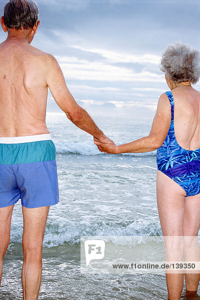Ein reifes Paar  das am Strand Händchen hält.