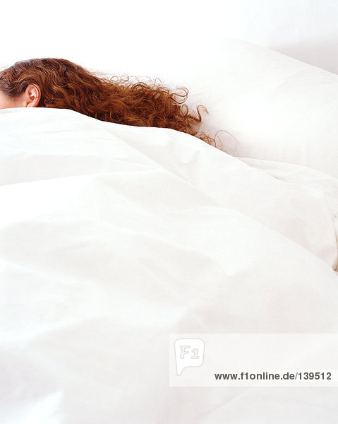 Eine Frau schläft in einem gemütlichen Bett.