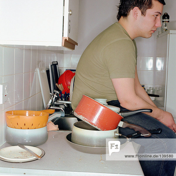 Junge sitzend in einer unordentlichen Küche