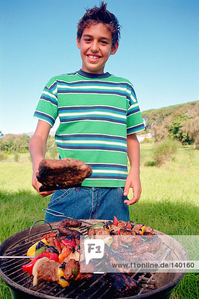 Boy cooking meat on barbeque