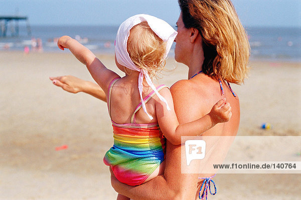 Woman carrying a toddler on the beach