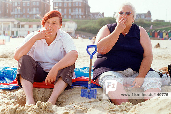 Zwei Frauen rauchen am Strand