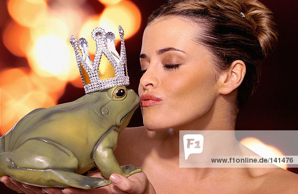 Frau küsst Spielzeugfrosch