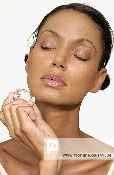 Woman holding ice cube on face