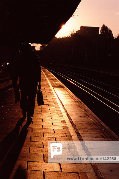 Silhouetted commuter on railroad platform