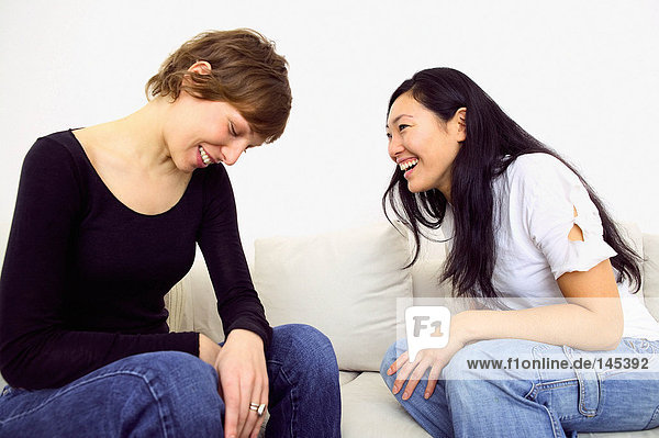 Two women laughing on sofa