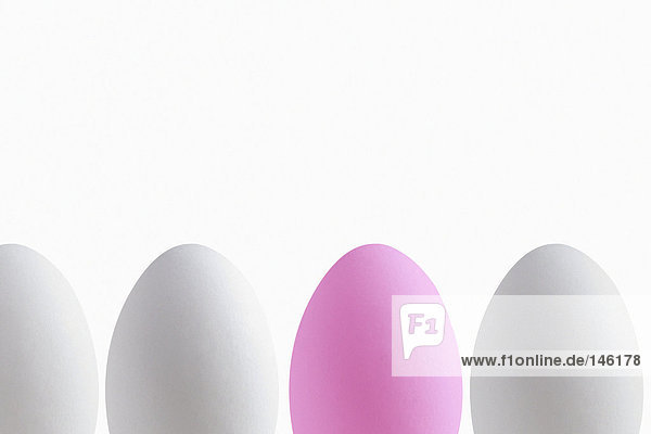 Pink egg in a row of white eggs