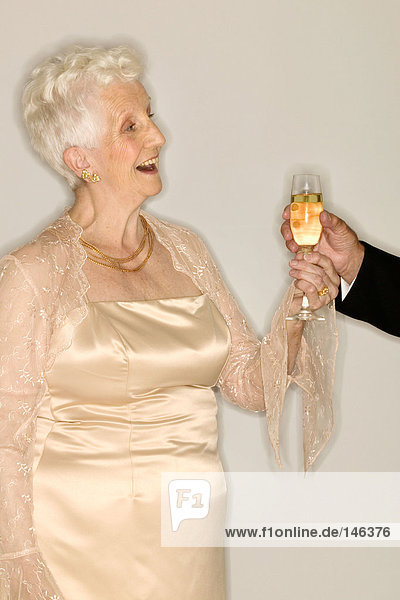 Seniorin mit einem Glas Champagner