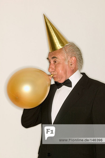 Senior Mann beim Aufblasen eines Ballons