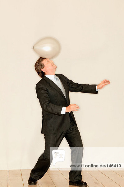 Mann  der einen Ballon auf dem Kopf balanciert.