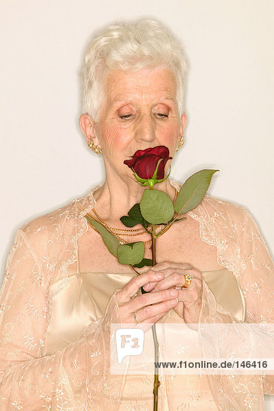 Seniorin schnüffelt Rose