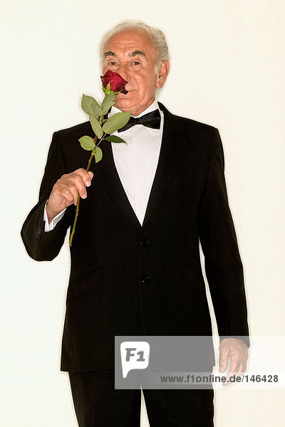 Senior Mann schnüffelt rote Rose