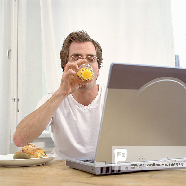 Mann beim Frühstück mit Laptop