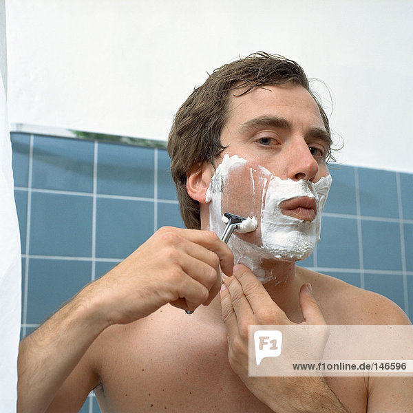 Mann rasiert sich im Spiegel