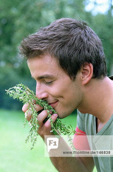 Young man smelling rosemary