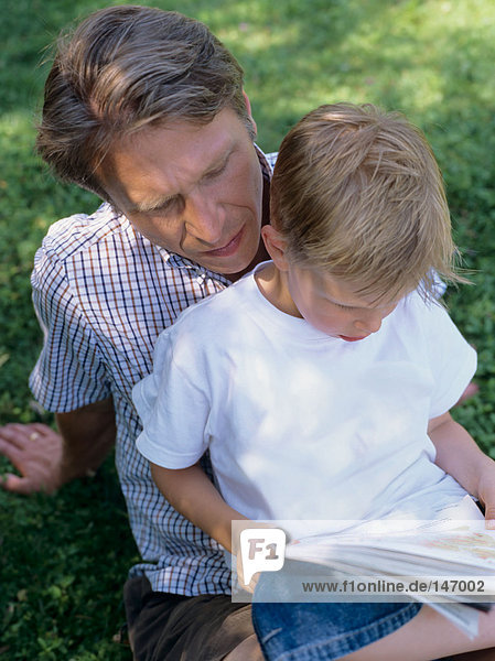 Vater und Sohn beim Lesen im Freien