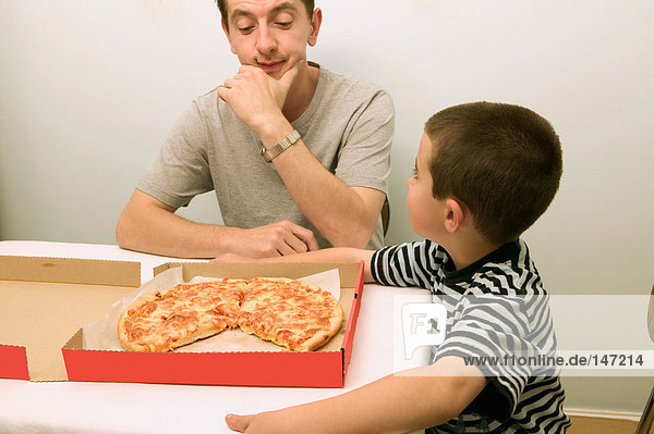 Father and son looking at a pizza