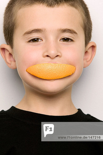 Boy with an orange segment in his mouth