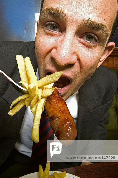 Businessman eating french fries and a sausage