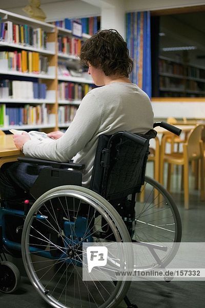 Disabled man reading in library