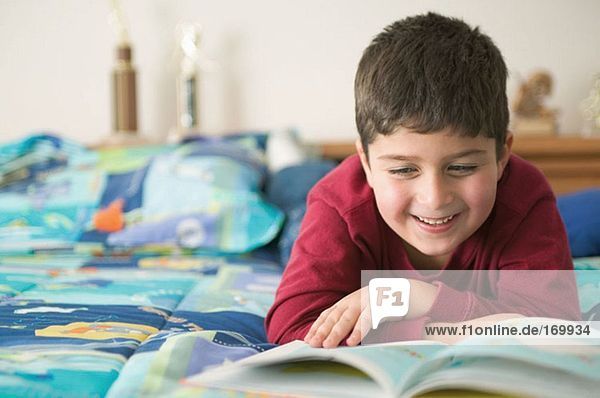 Junge liest ein Buch und lächelt