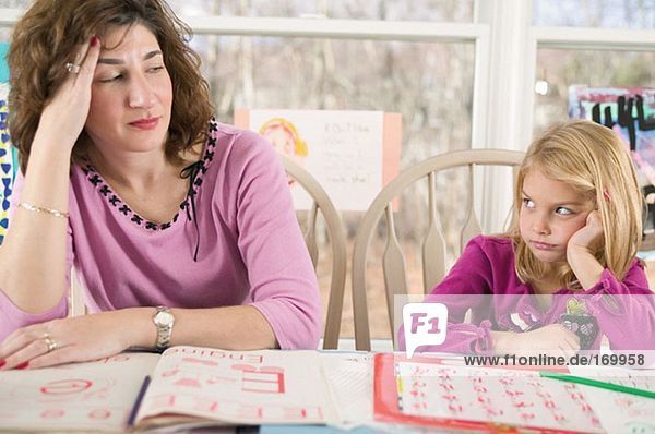 Frustrierte Mutter hilft gelangweilter Tochter bei den Hausaufgaben