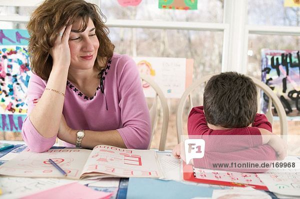 Mutter hilft dem müden Sohn bei den Hausaufgaben