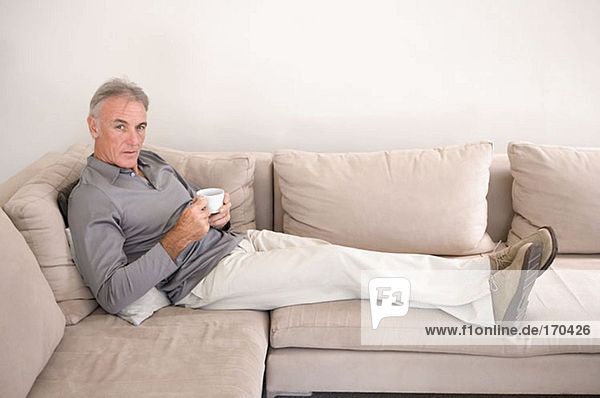 Man on sofa holding teacup