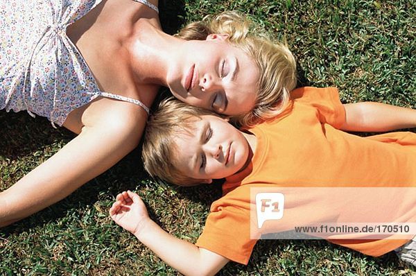 Mutter und Sohn schlafen auf dem Rasen.
