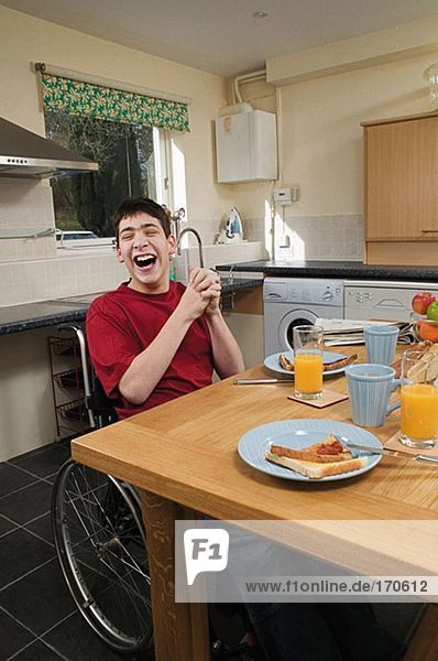 Behinderter Mann lacht am Frühstückstisch
