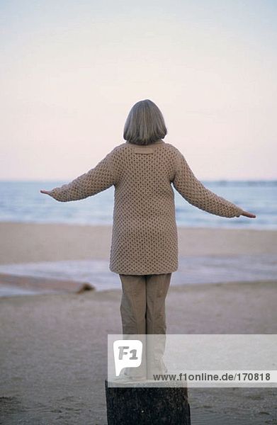 Seniorin beim Balancieren auf einem Baumstamm