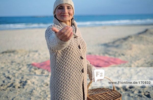 Seniorenfrau hält Picknickkorb und winkt