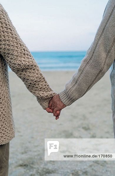 Paar hält sich am Strand an den Händen