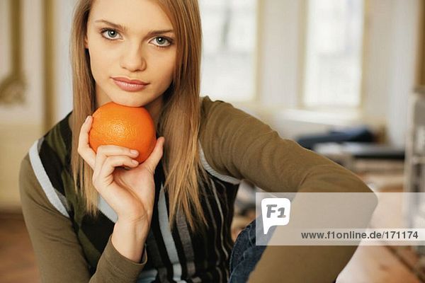 Woman holding an orange under her chin