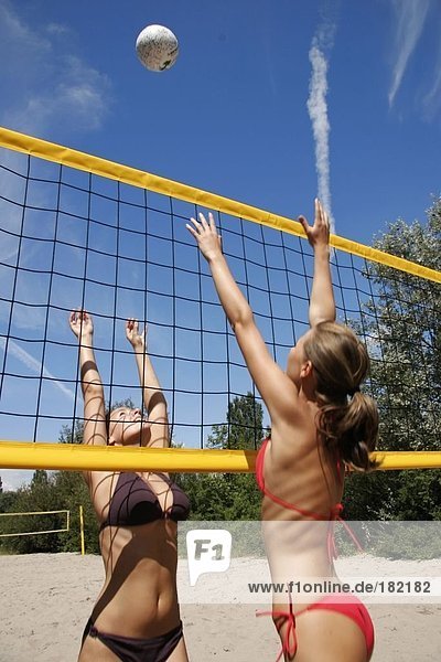 Rear view of two young women playing volleyball