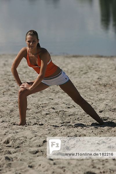 Portrait of young woman doing yoga on lake beach