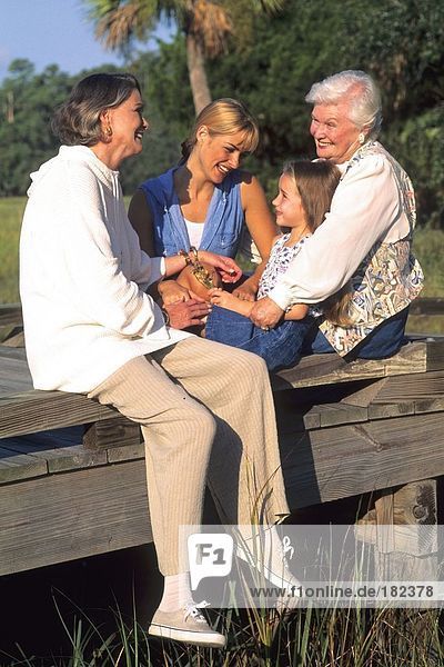 Drei Generation Familie auf Holzbrett mit Freund sitzend