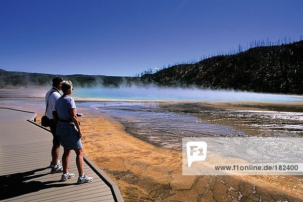 Tourists standing on boardwalk looking at hot spring  Yellowstone National Park  Wyoming  USA