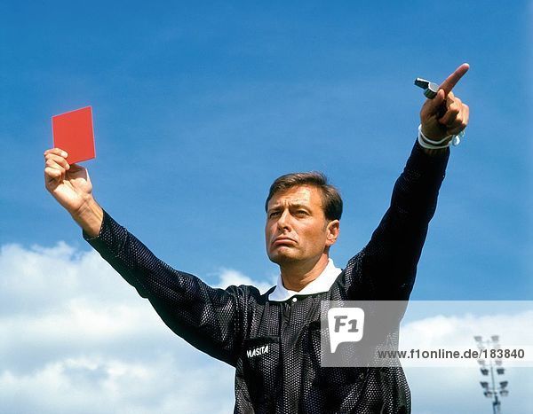 Soccer referee holding up red sending off card