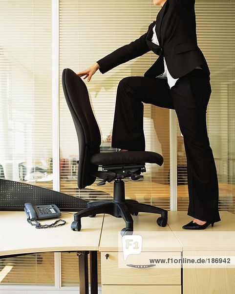 Geschäftsfrau auf einem Bürostuhl stehend