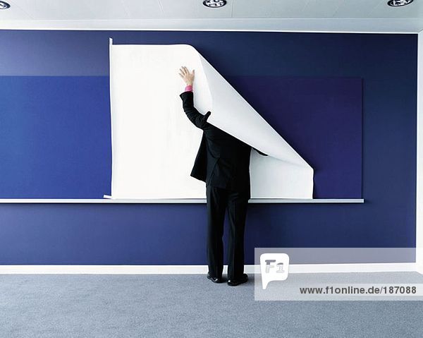 Geschäftsmann befestigt Papier an der Wand