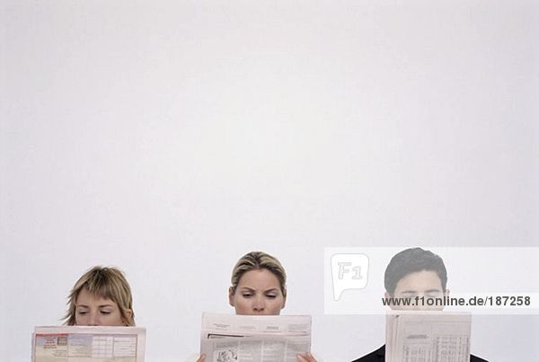 Three people reading newspapers