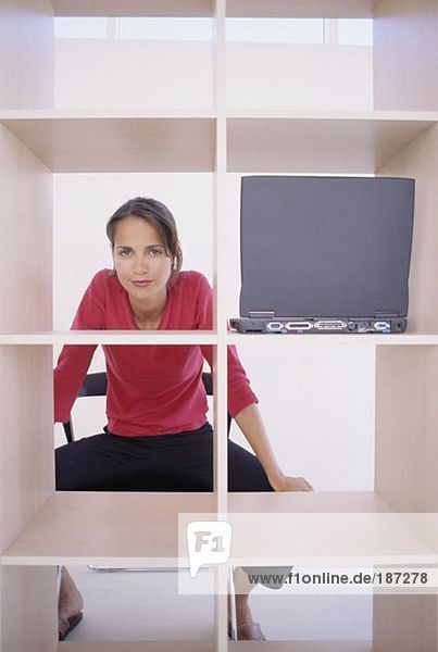 Woman sitting behind bookcase
