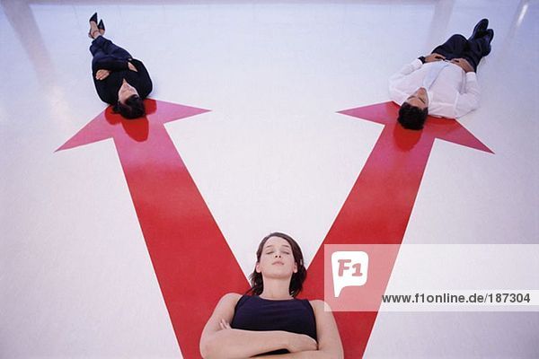 Three people lying on arrow signs