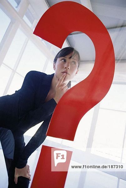Woman behind large question mark