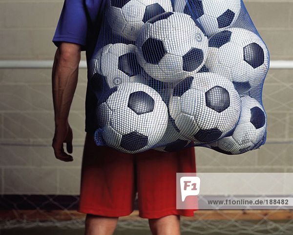Fußballspieler mit einer Tasche voller Fußbälle