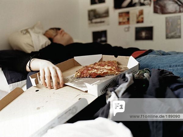 Boy sleeping with pizza on bed